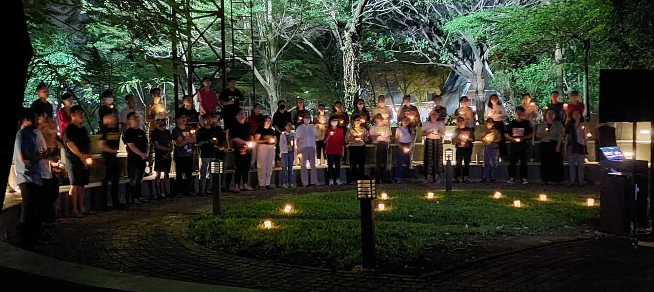 Paduan suara memegang lilin di amphitheater pada malam hari