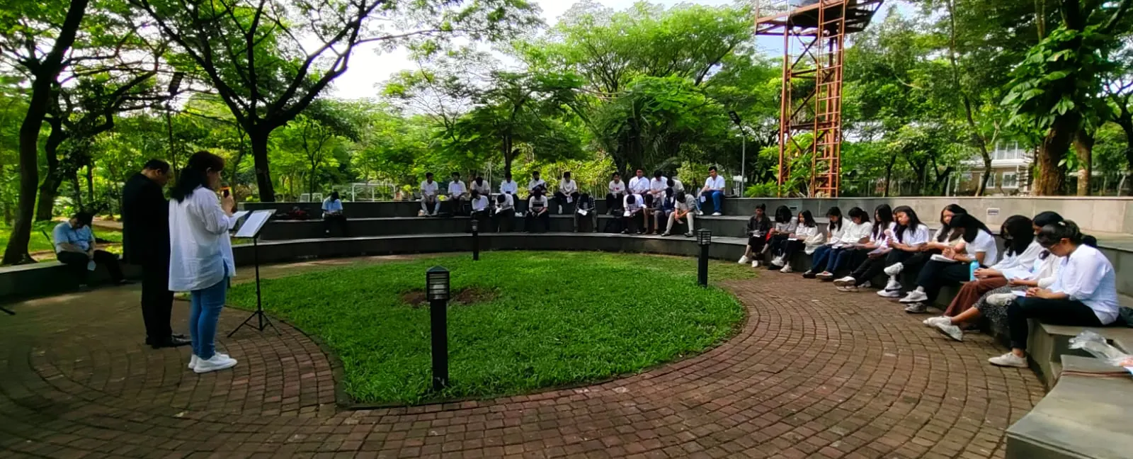 Remaja duduk di tribun melingkar amphitheater pada siang hari