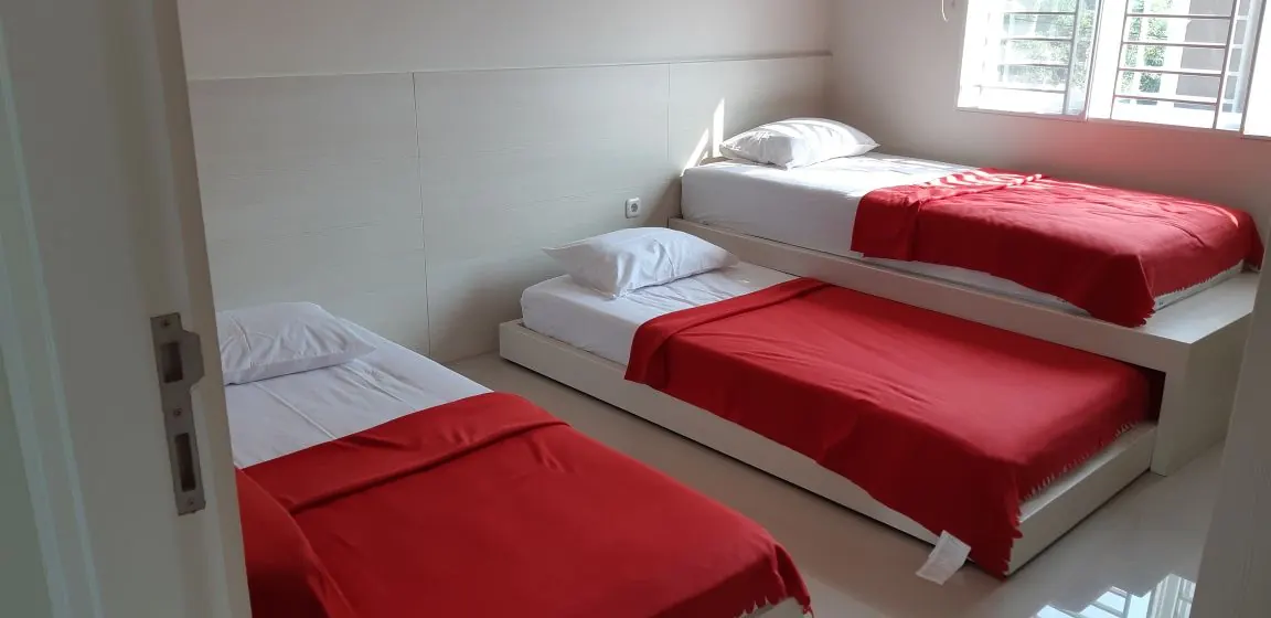 Kamar tidur dengan ranjang bertingkat rendah dan selimut merah