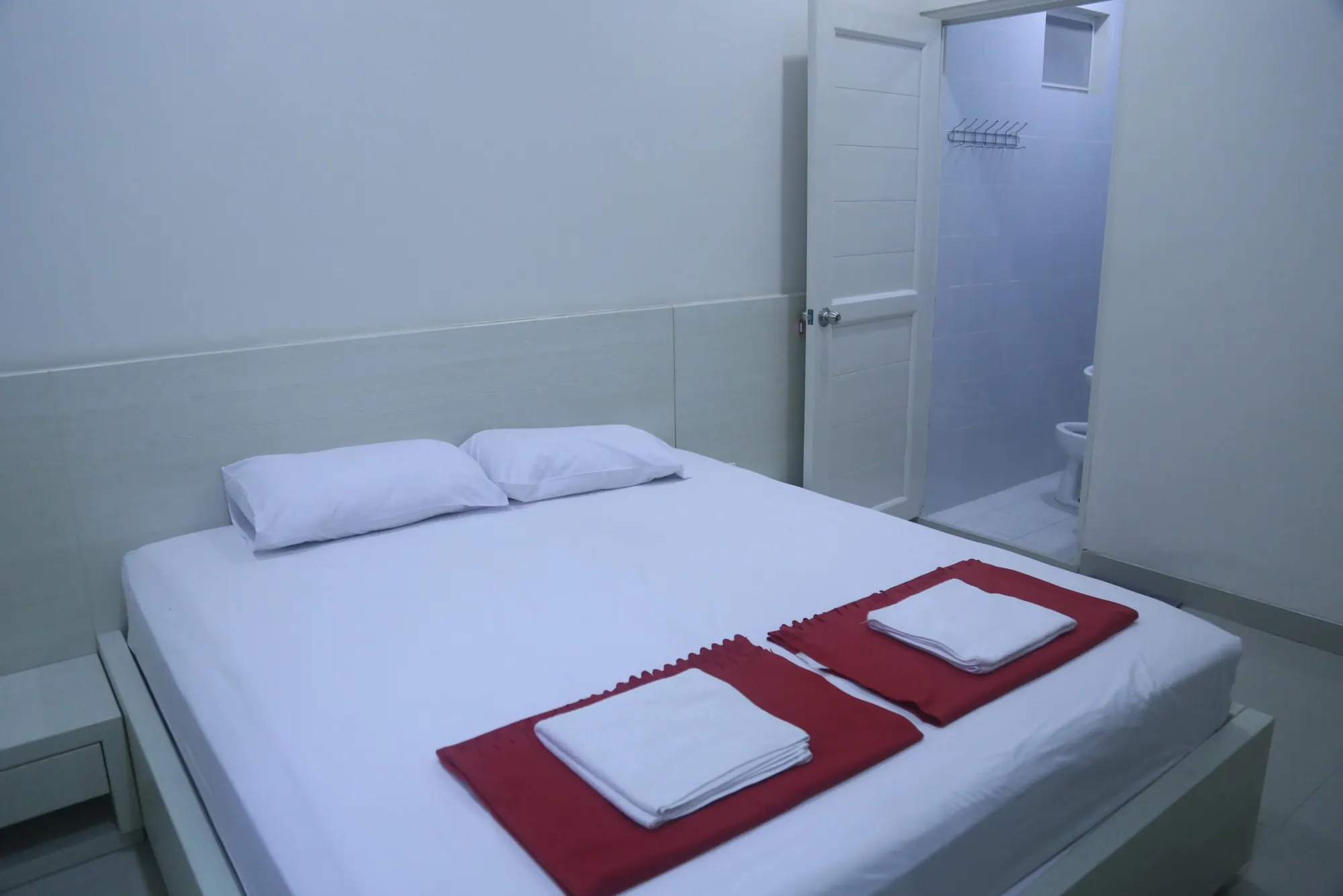 Kamar tidur dengan ranjang besar dan handuk merah yang terlipat