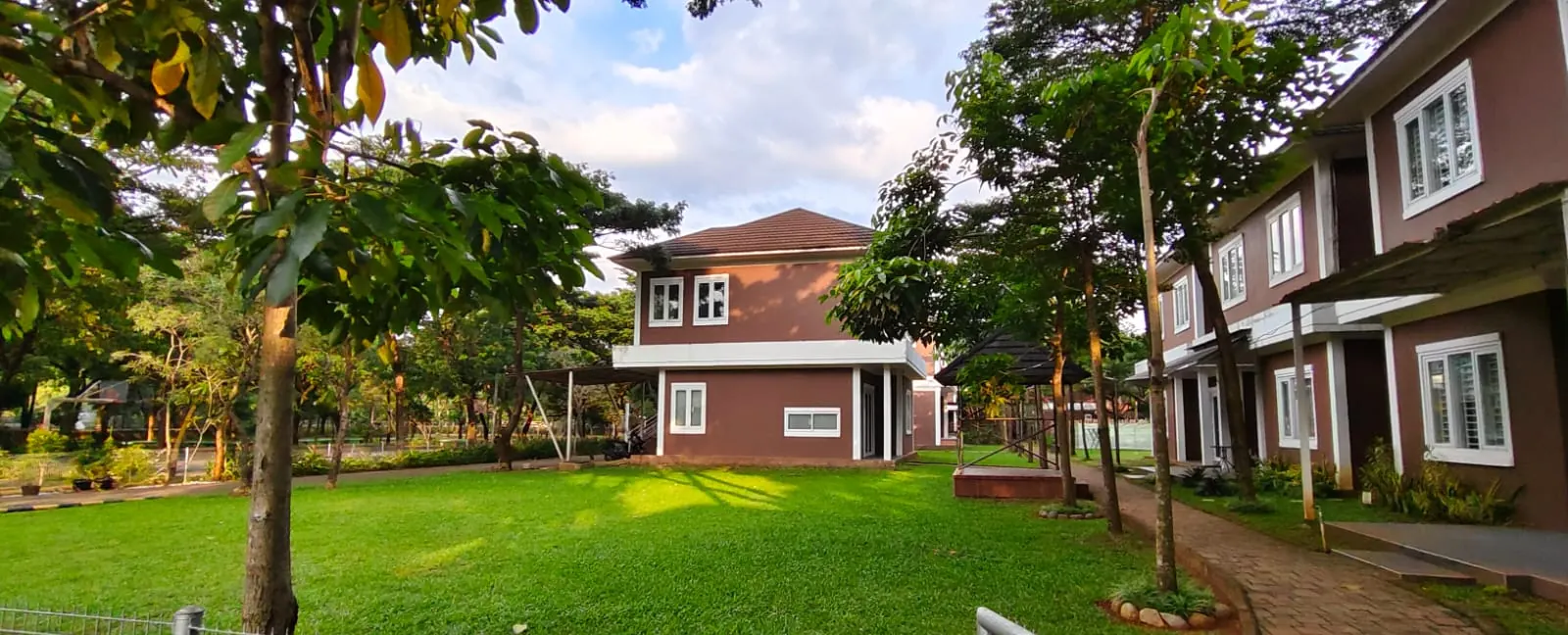 Rumah penginapan bata merah dengan taman dan pepohonan